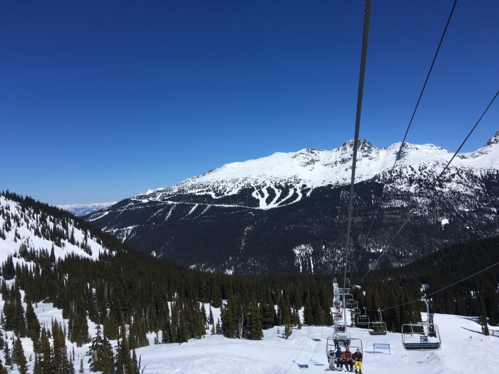 Whistler mountain ski hill showing a chairlift and a mountain in the background.
